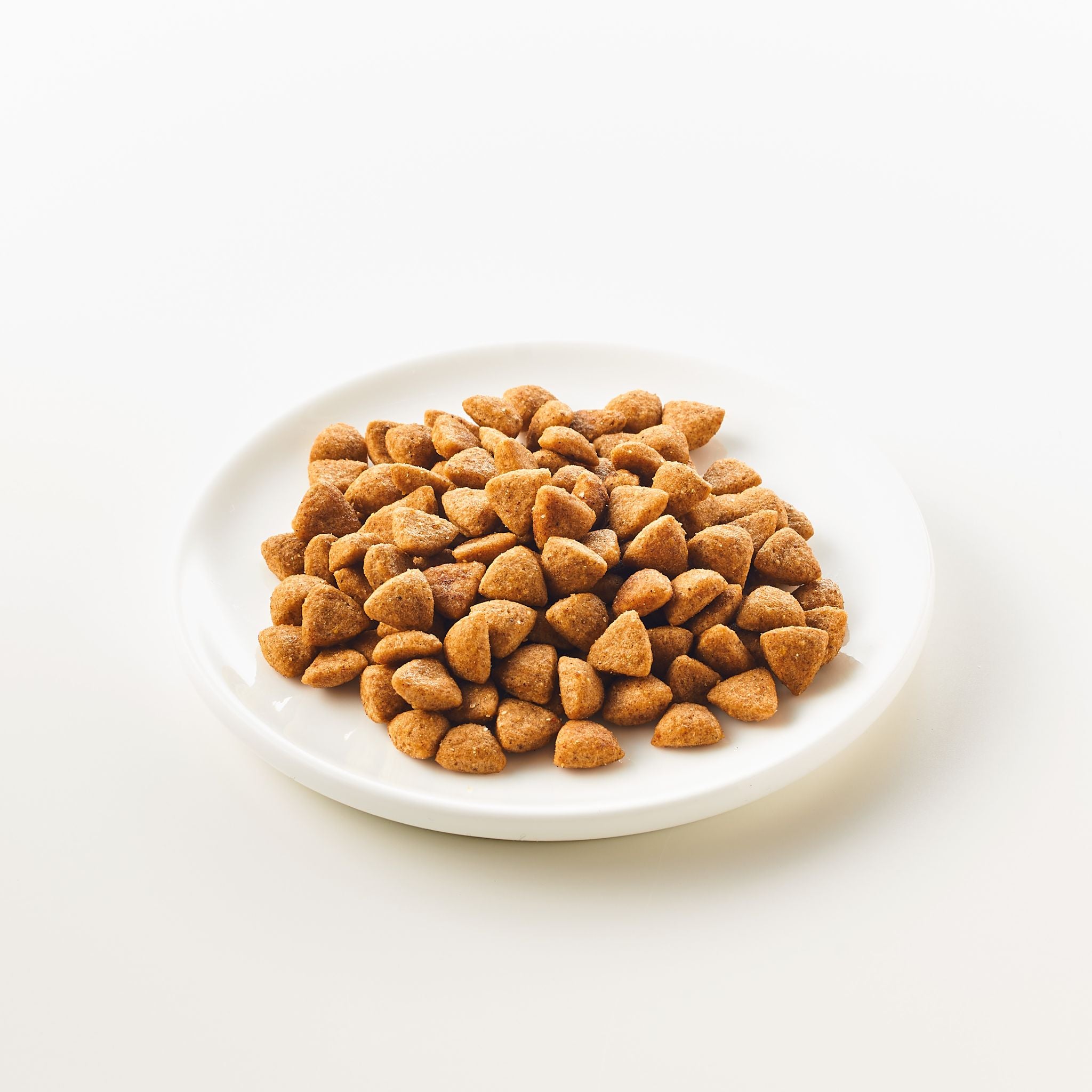 Eine Schale, die mit Katzenfutter gefüllt ist. Die Körner sind klein und braun und sehen wie Trockenfutter aus.